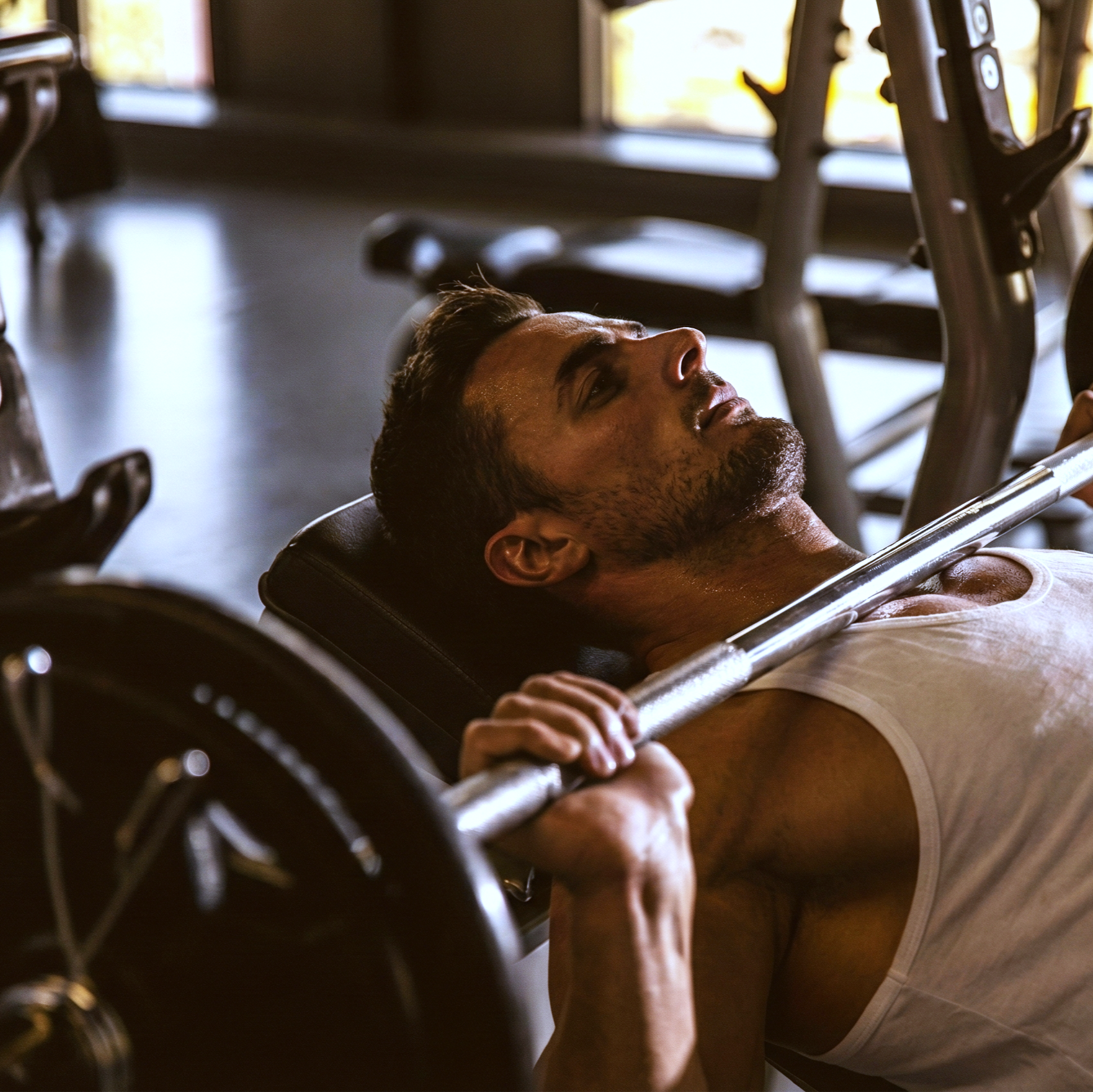 Man performing bench press in a gym during strength training workout.